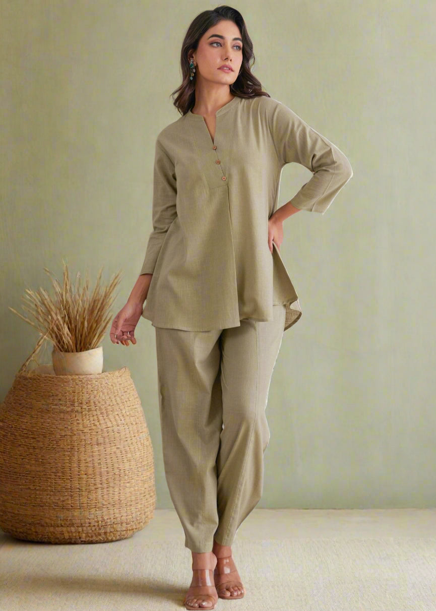 Woman wearing a green outfit standing against a decorative wall.