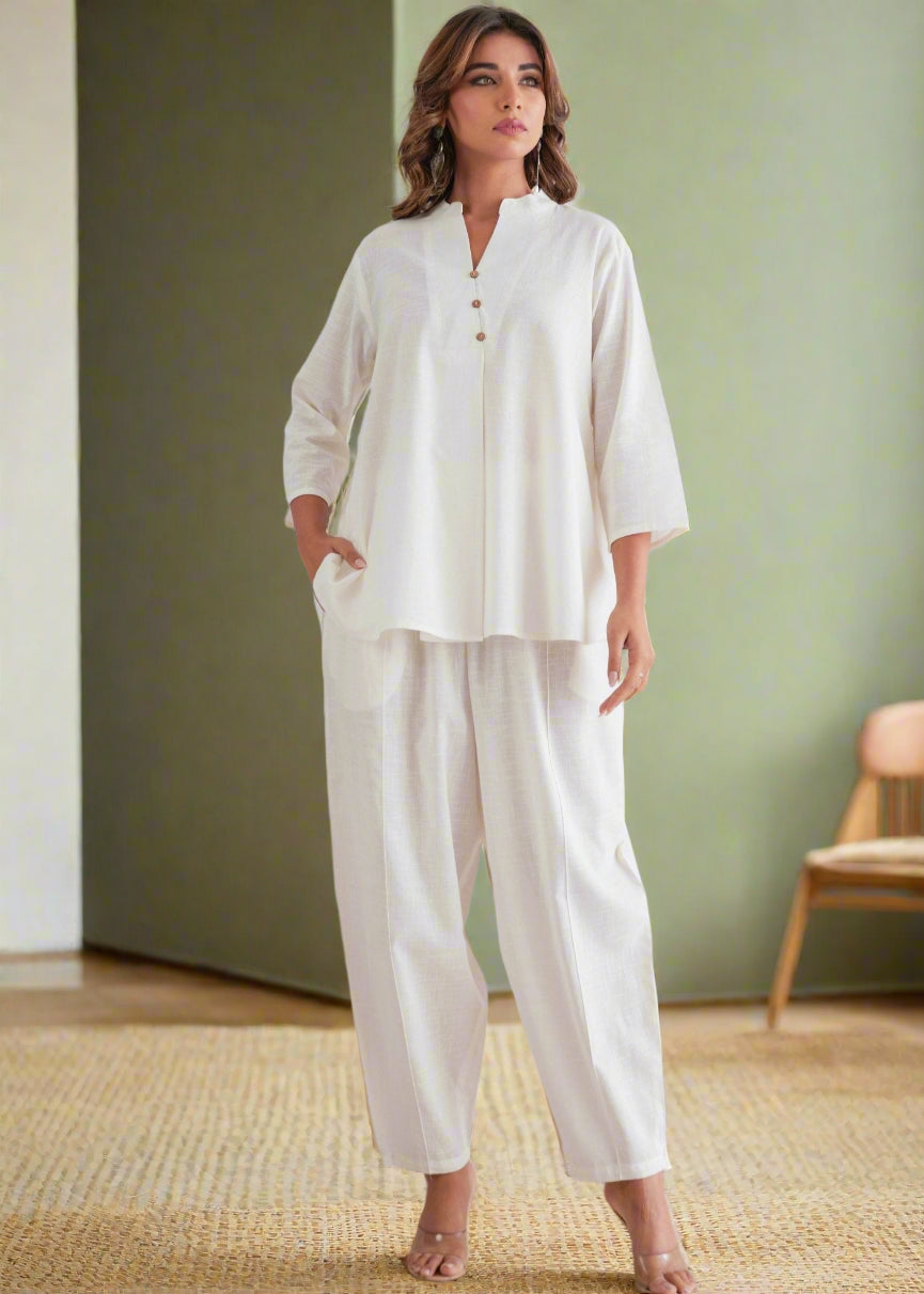 Woman wearing a white outfit against a decorative wall.