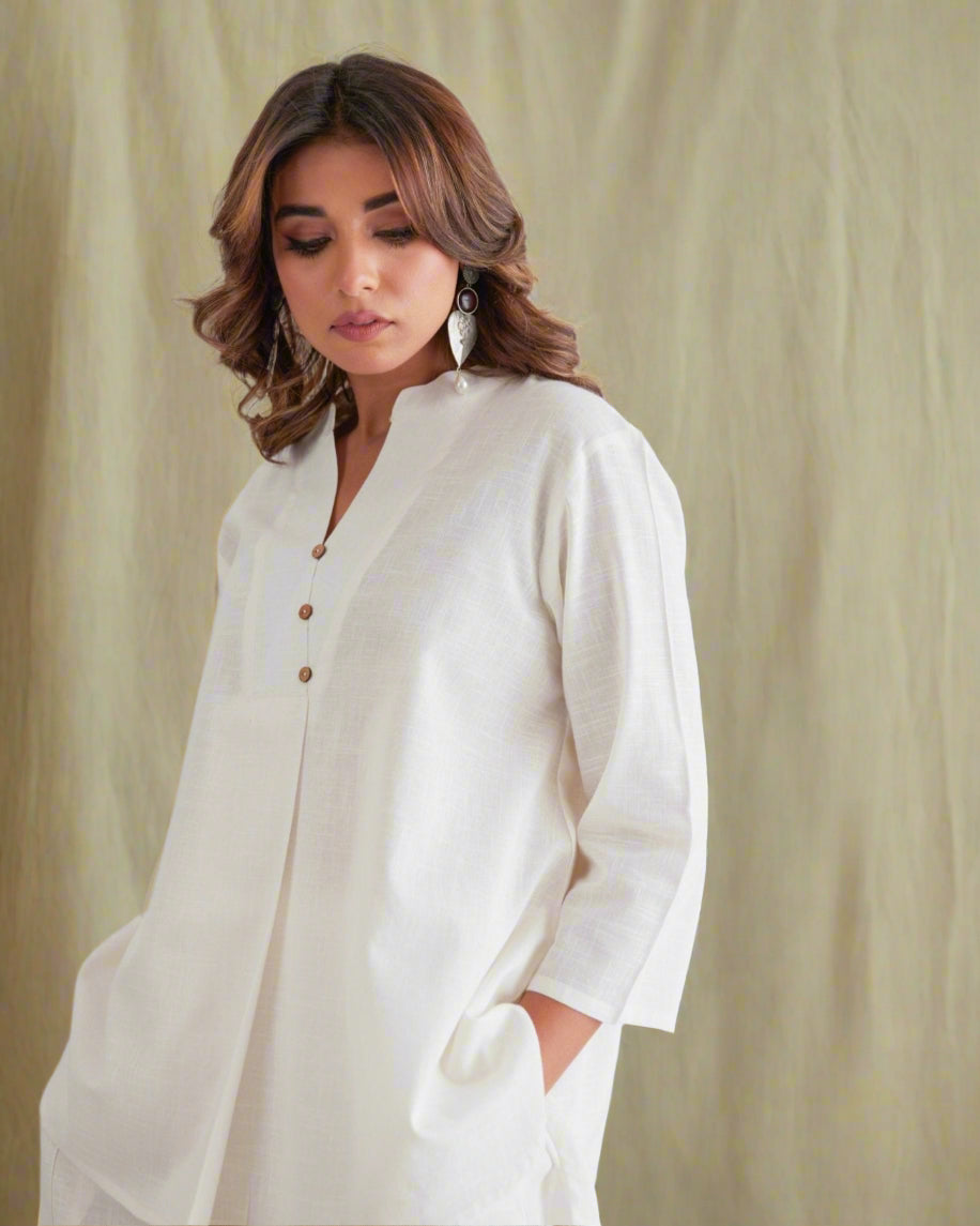 Woman wearing a white outfit with a peacock design in the background