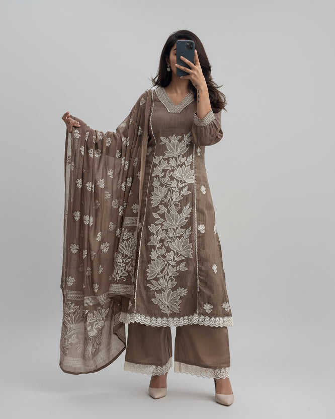 Woman wearing a brown embroidered outfit with a matching dupatta in a room.