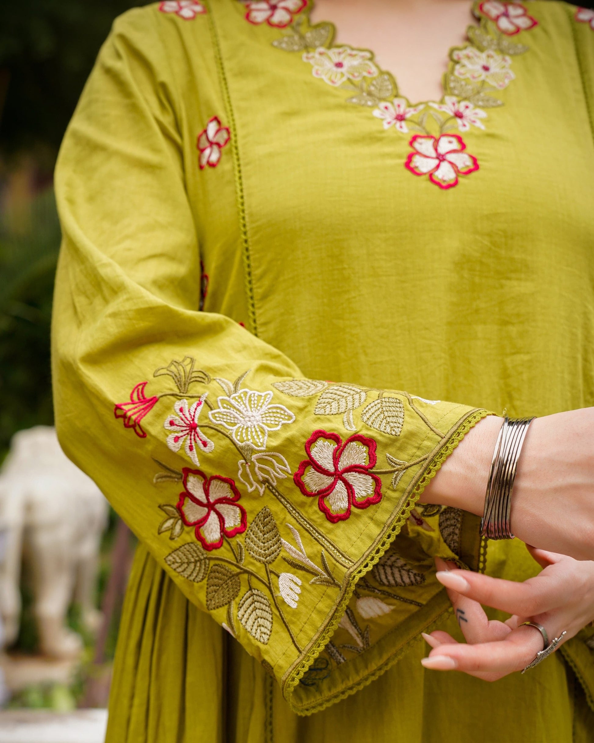 Green embroidered garment with floral patterns on a blurred background