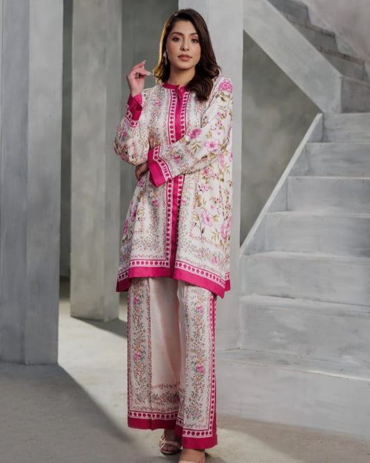 Woman in a traditional outfit with pink and white patterns standing in a modern architectural setting.